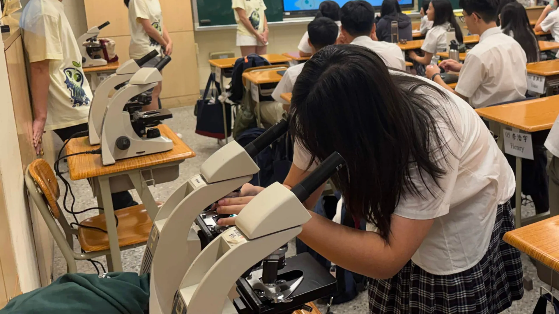 A high school student looking through a microscope at onion cells during the plasmolysis experiment.