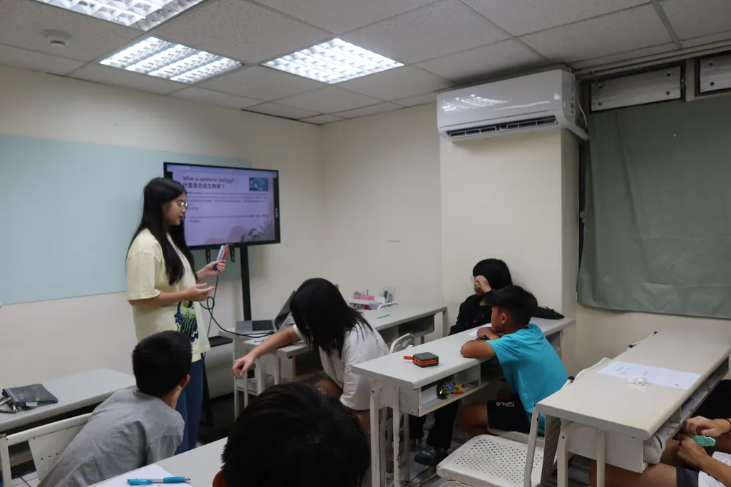 A team member presenting to a junior high class in front of a screen, with students seated at desks.