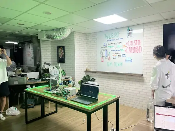 The bioreactor set on a green-lit table in front of a whiteboard.