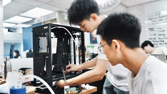 Two students fitting the bioreactor into a black computer case.