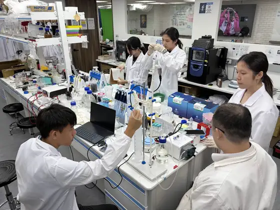 Students and instructors working on the bioreactor at a lab bench.