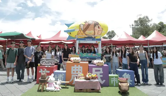 The team gathered in front of a festival stage at the Taipei Expo farmers' event.