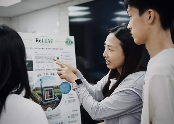 Two students pointing at the ReLEAF poster.