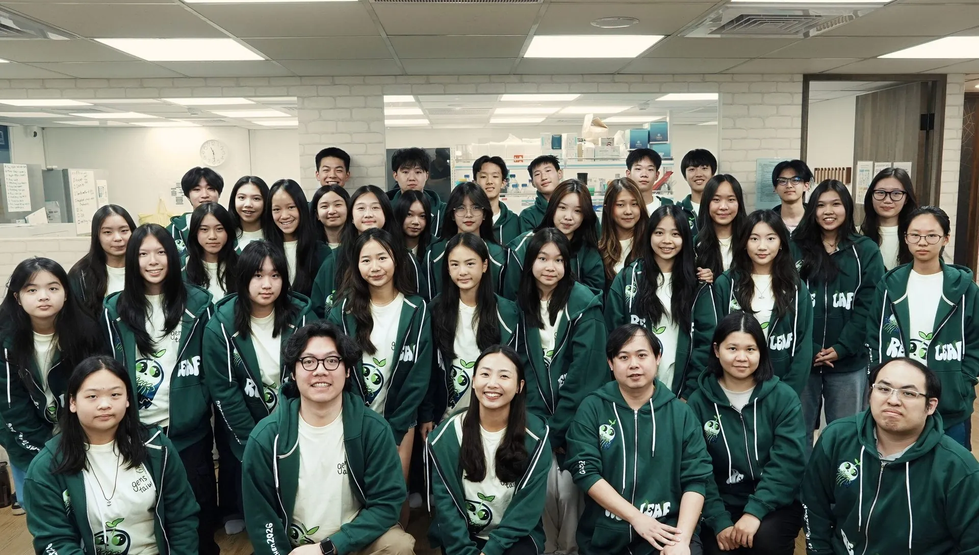 The ReLEAF team, about forty students in green team jackets, standing and crouching in rows in the lab.