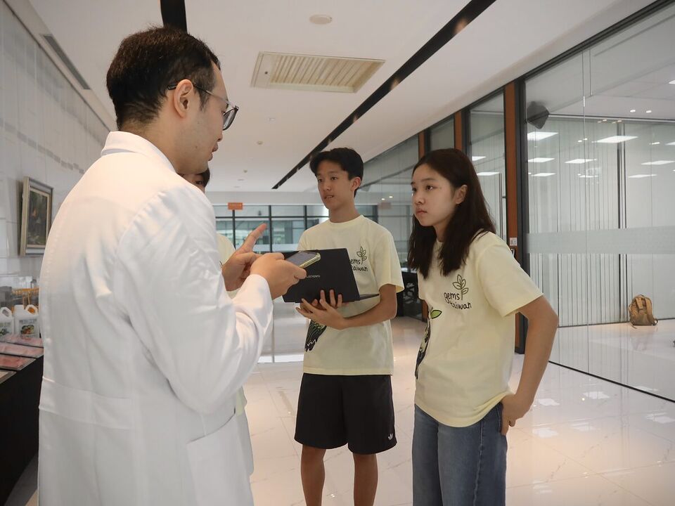 At CH Biotech, a researcher in a white coat explains something to two ReLEAF students, who listen closely.