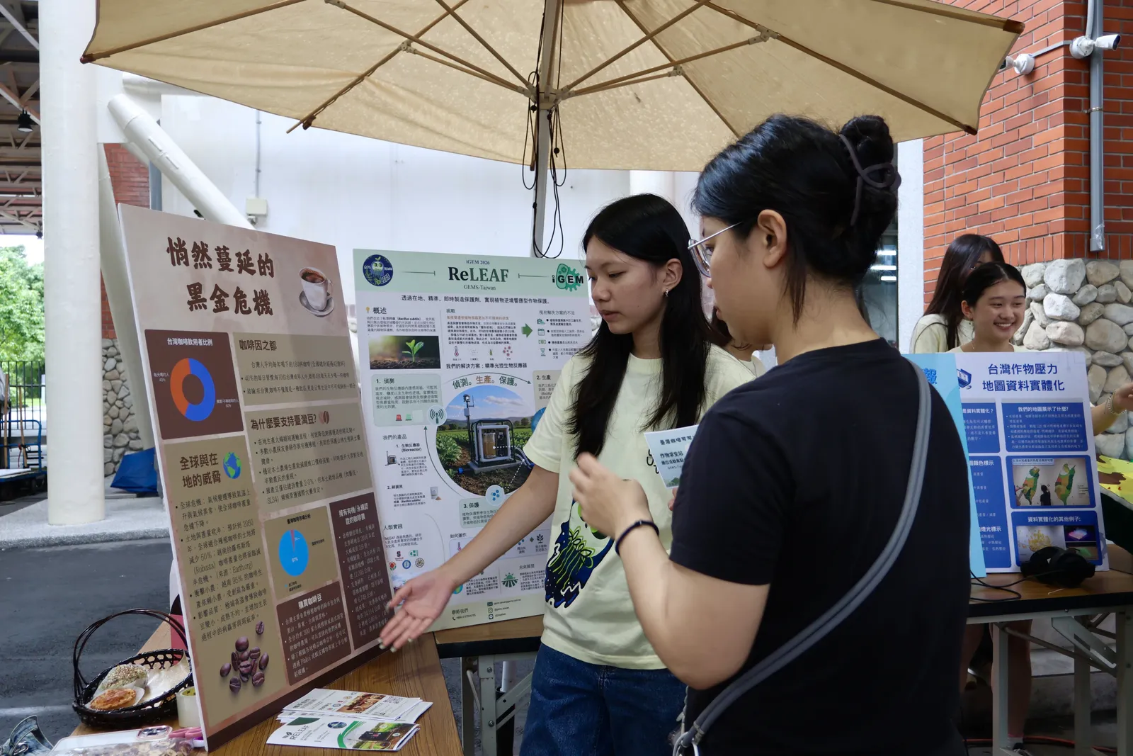 A student explains a coffee and climate poster to a visitor.