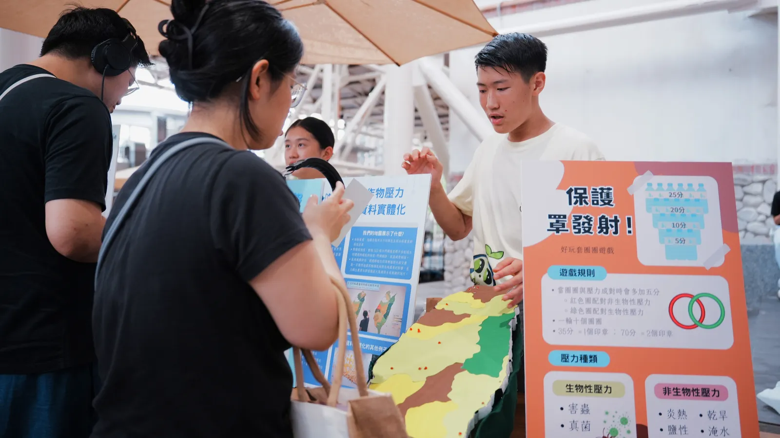A student explains a colour-coded map of Taiwan to two visitors.