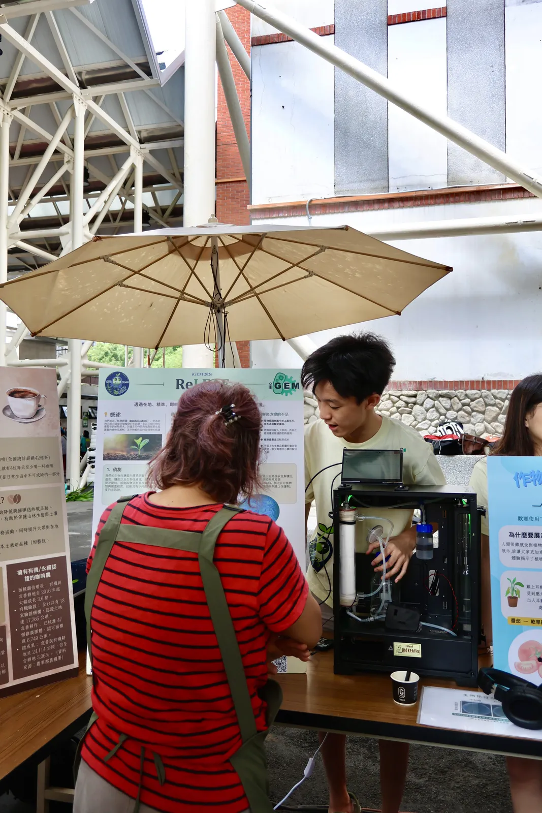 A visitor at the ReLEAF poster board beside the bioreactor prototype.
