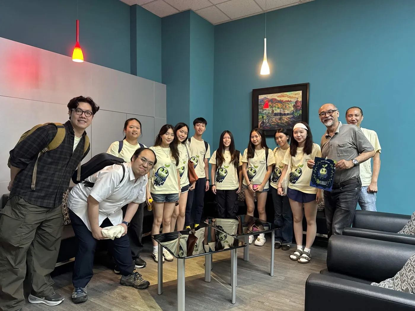 A group photo of the team with Prof. Huang in an office with teal walls.