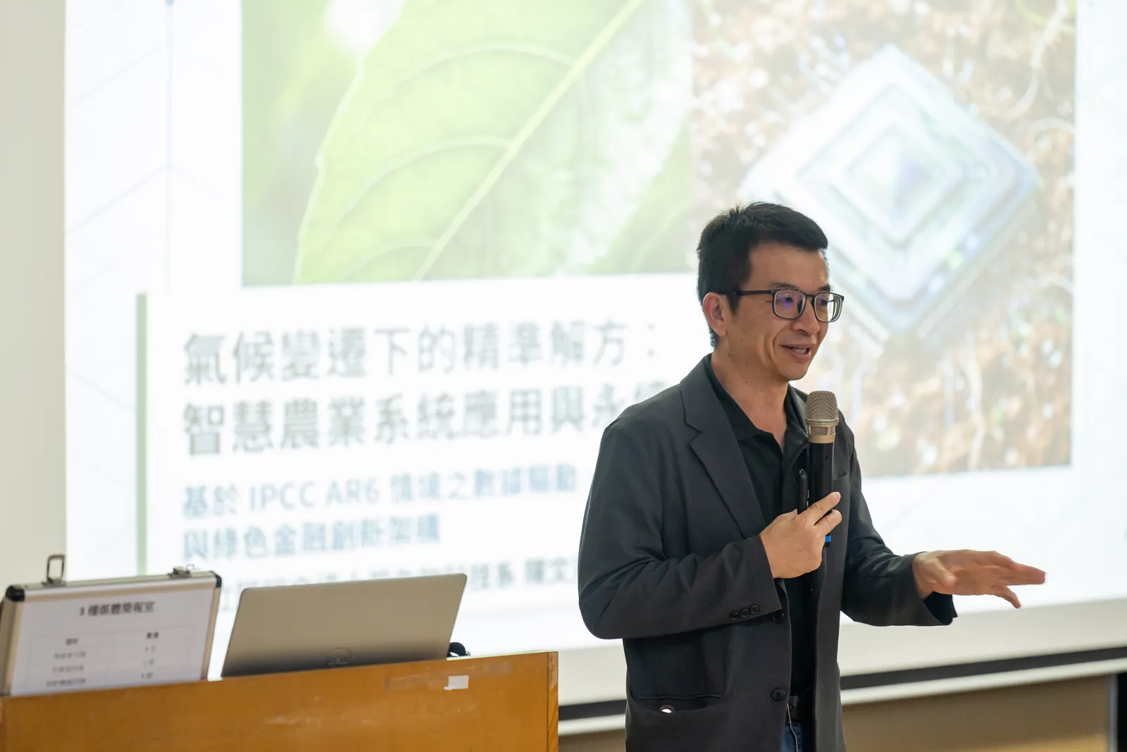 Prof. Chen speaking with a microphone in front of a slide about precision agriculture under climate change.