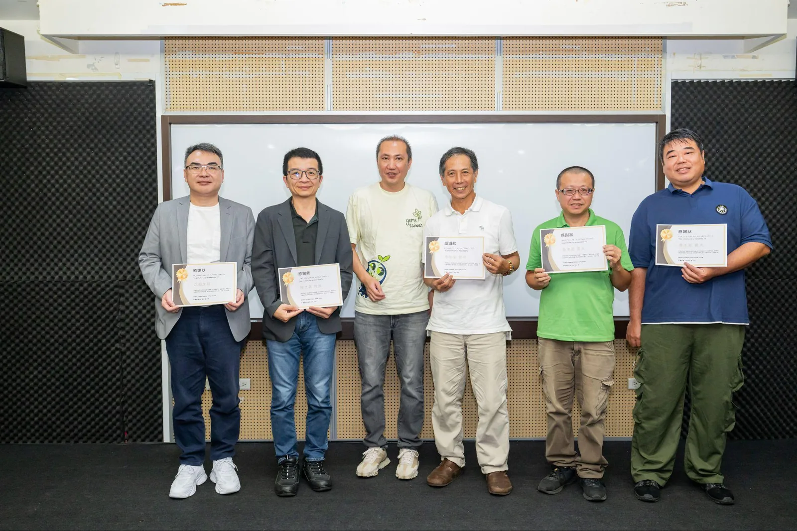 The forum speakers holding certificates in front of the screen.