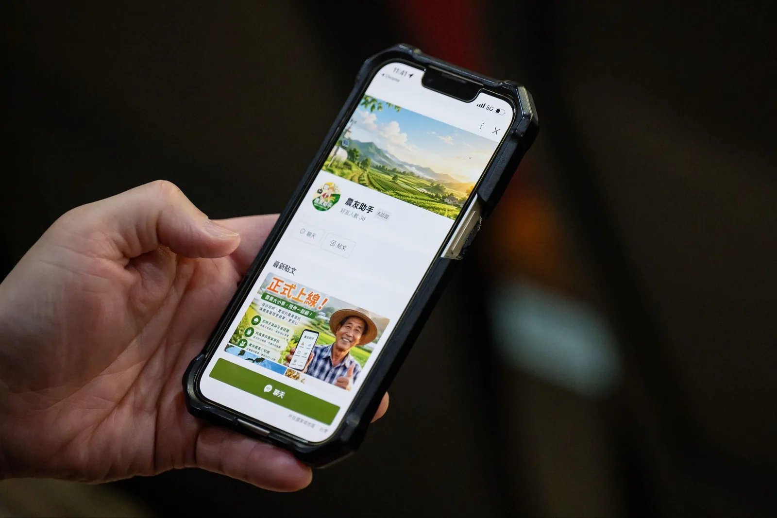 A hand holding a phone open on the 農友助手 LINE account.
