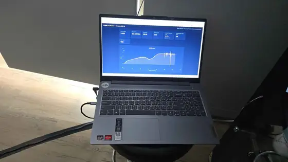A laptop on a dark bench displaying a long optical-density growth curve logged overnight from the inline photometer.