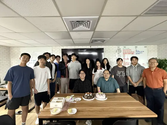The whole team and the instructors lined up behind a long wooden table at GEMS.