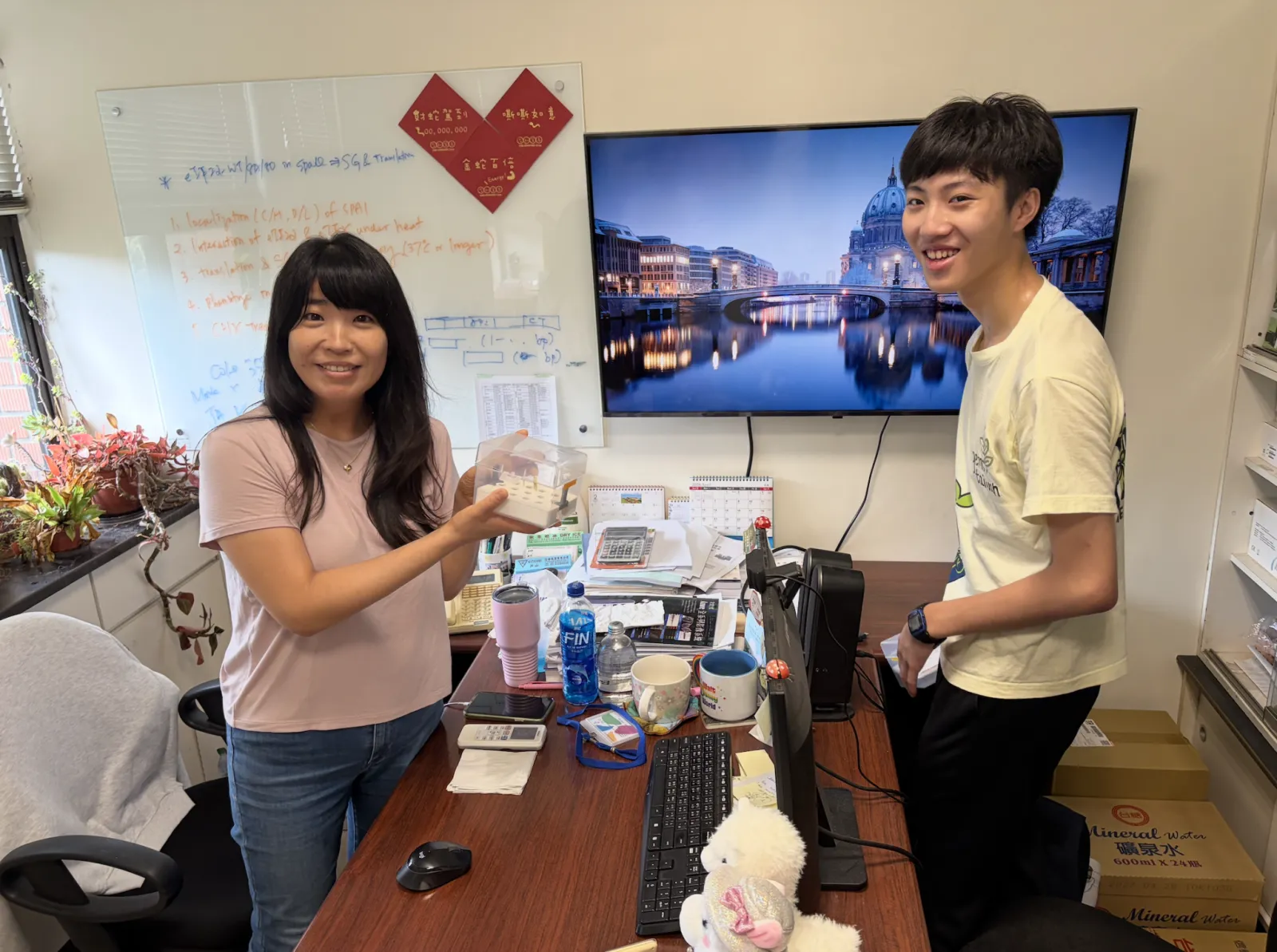 Prof. Cheng and a student standing together in her laboratory beside the team's hydroponic boxes.