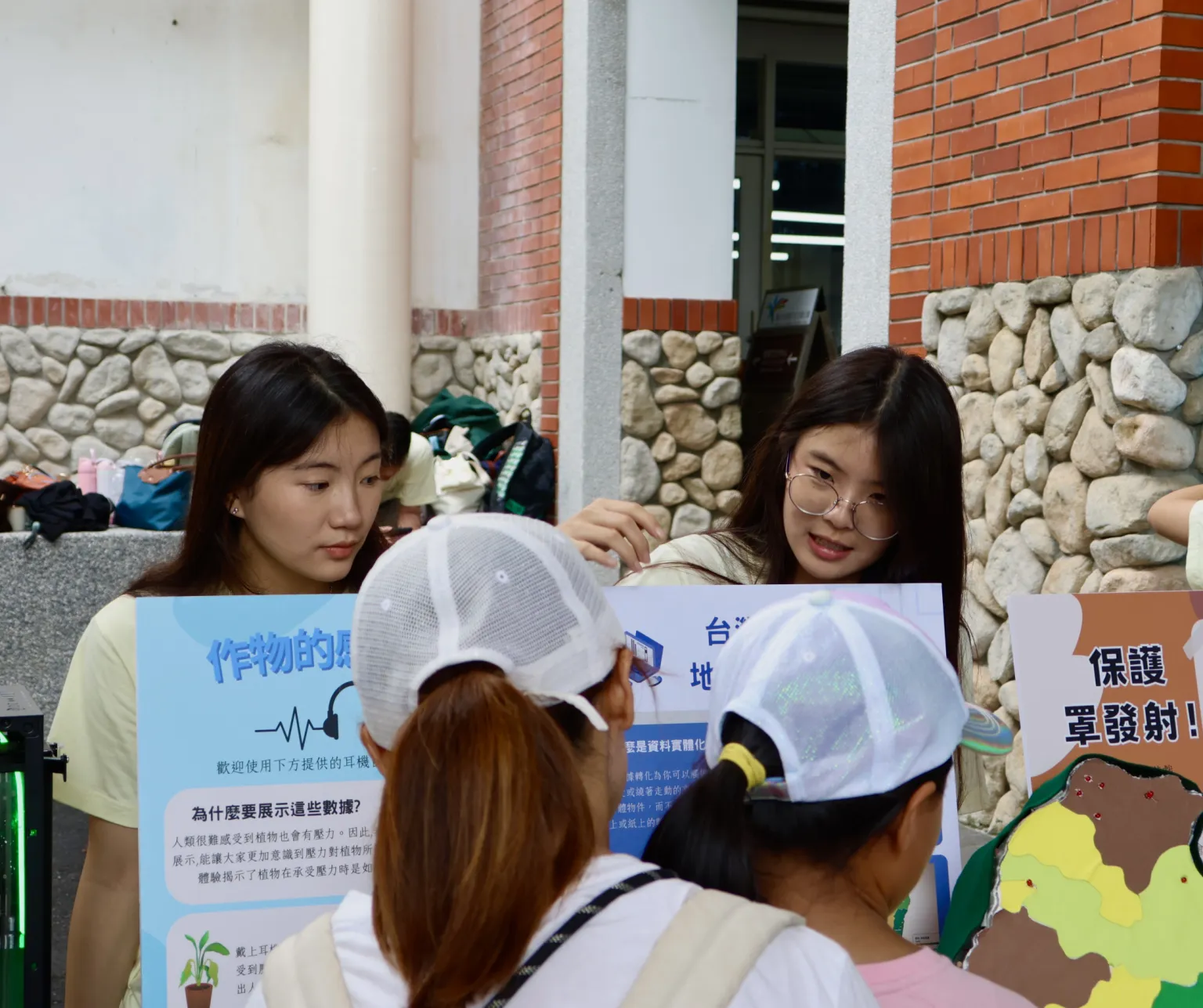 A team member explaining a map of crop stress across Taiwan to visitors at the booth.
