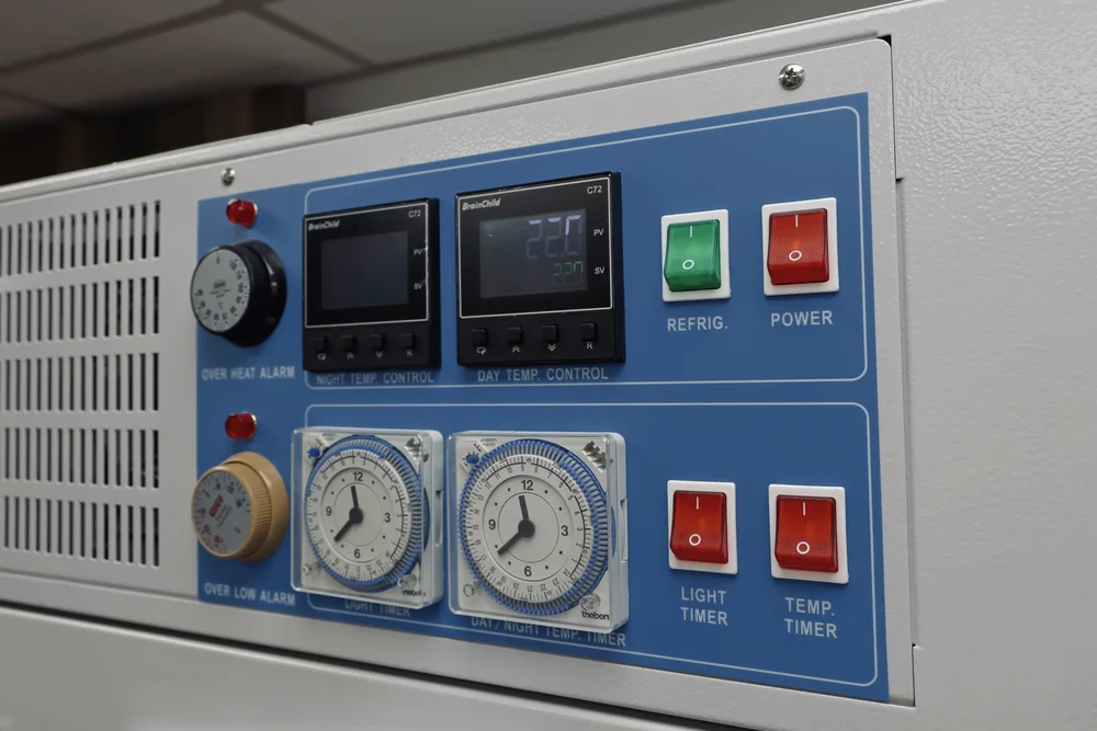 The control panel of the growth chamber: temperature controllers, two analogue light timers and power switches.