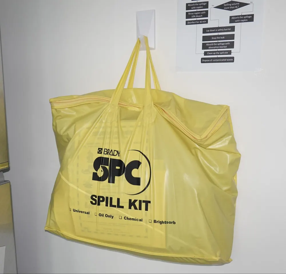 A yellow bag labelled SPC Spill Kit hanging on a white wall.