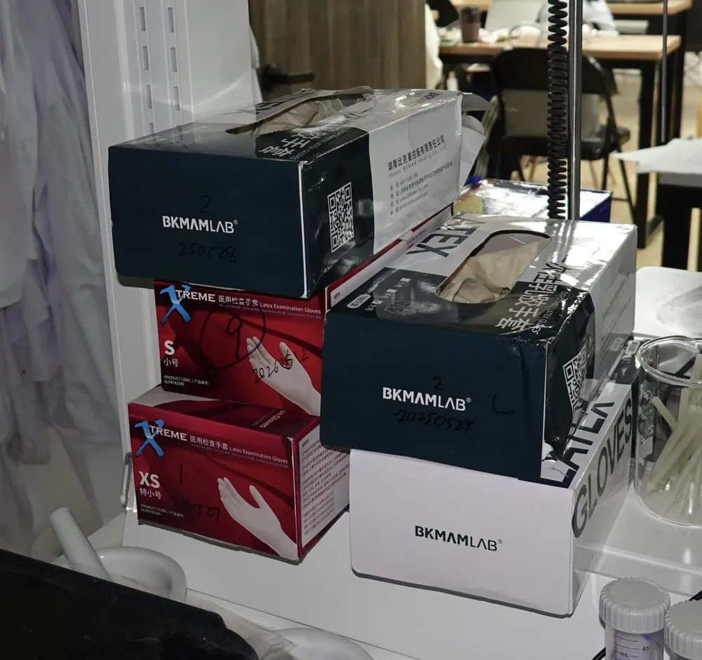 Open boxes of examination gloves in sizes XS and S on a bench.