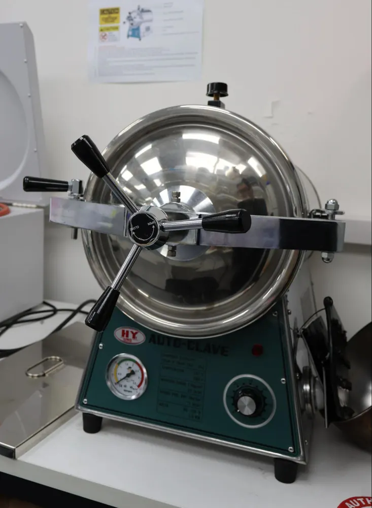 A benchtop autoclave with a round stainless steel lid and a control panel.