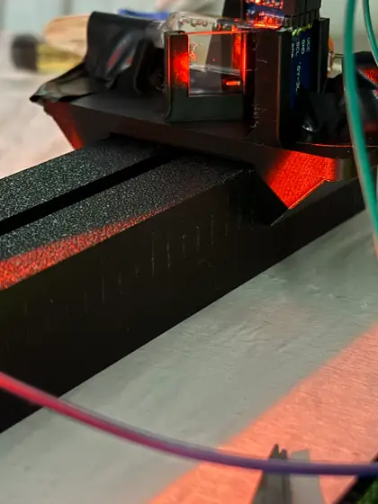 Close-up of V1: an optic seated in its printed mount on the rail, lit by the LED