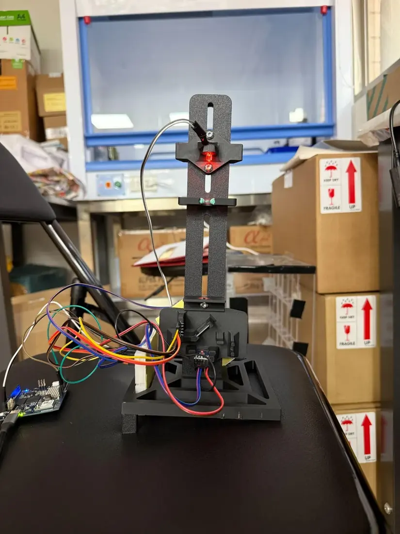 The photometer column tilted on its printed wedge stand, LED lit at the top, wired to the controller
