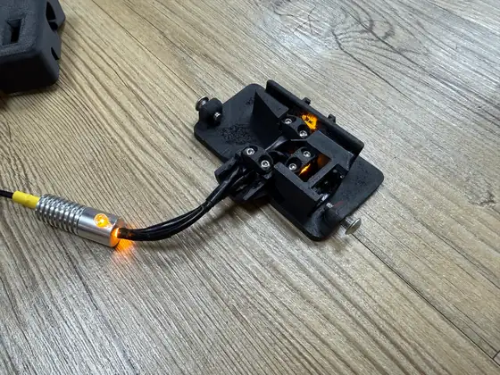 The Slim photometer's open body on a wooden table, its two fibers running in from the lit aluminum fiber illuminator