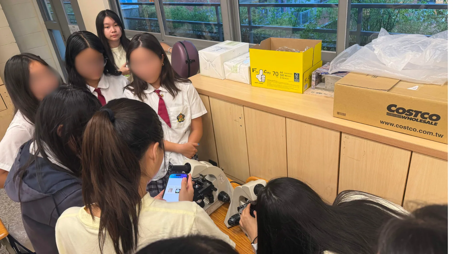 High school students and team members at a bench with microscopes, observing prepared onion cell slides.