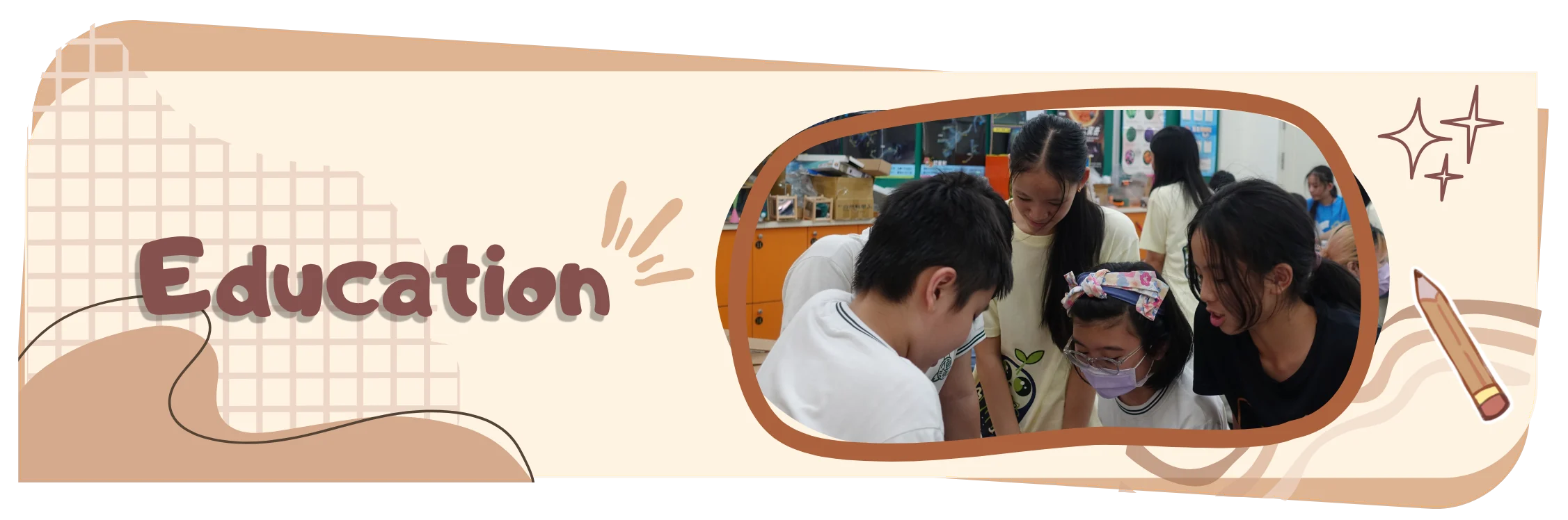 Education. Four schoolchildren lean in over a desk together while a team member in a ReLEAF shirt watches from behind them in a classroom.
