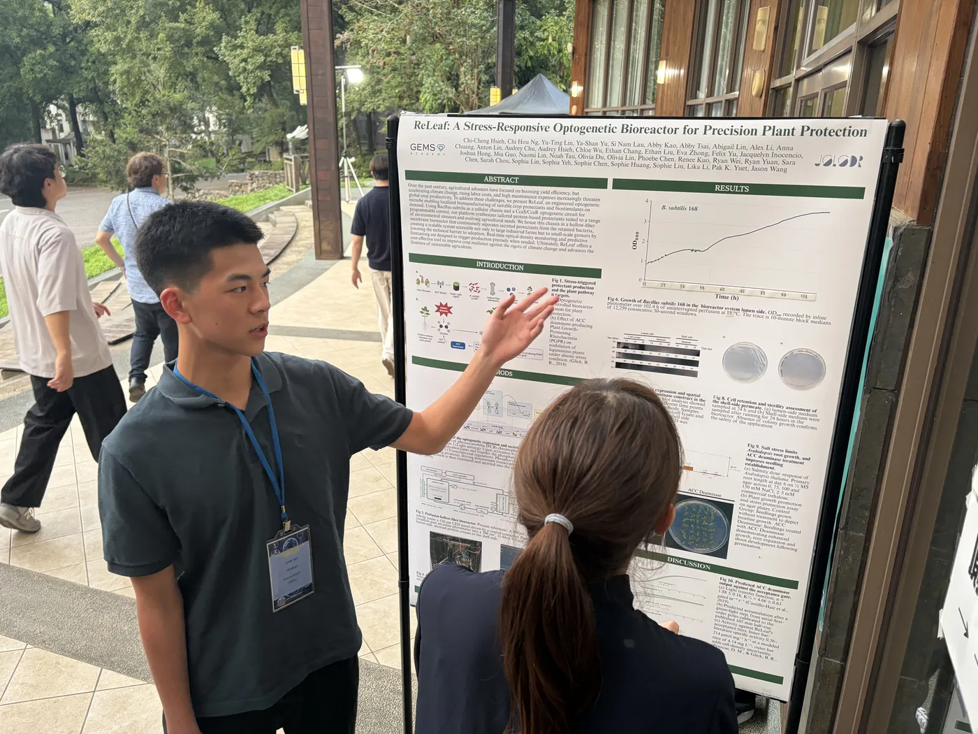 A student pointing at a results graph on the poster for a visitor.