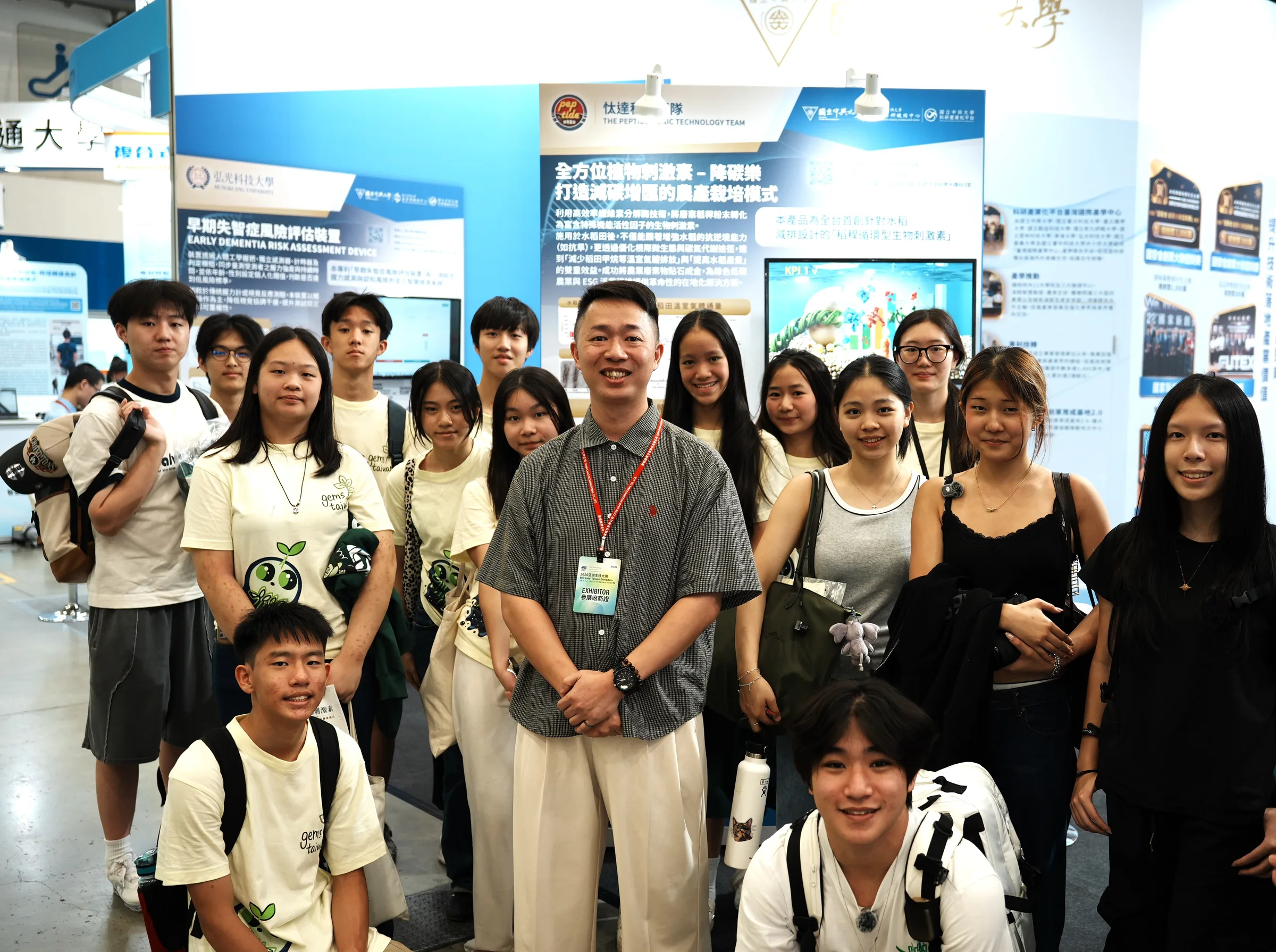 The team with an exhibitor wearing a lanyard in front of display panels at the exhibition.