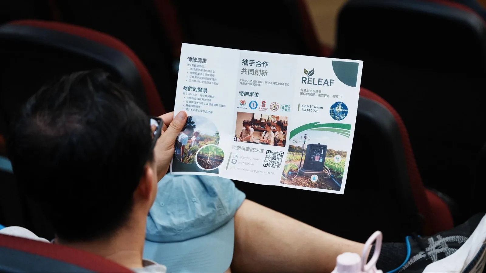 A hand holding the ReLEAF brochure at the forum.